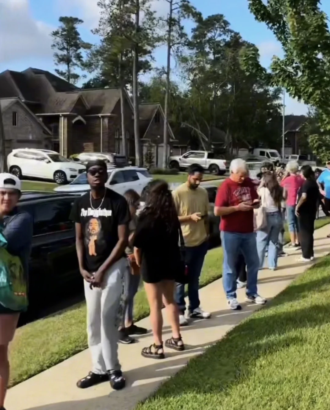 Shoppers waiting along a neighborhood sidewalk before a J and M estate sale