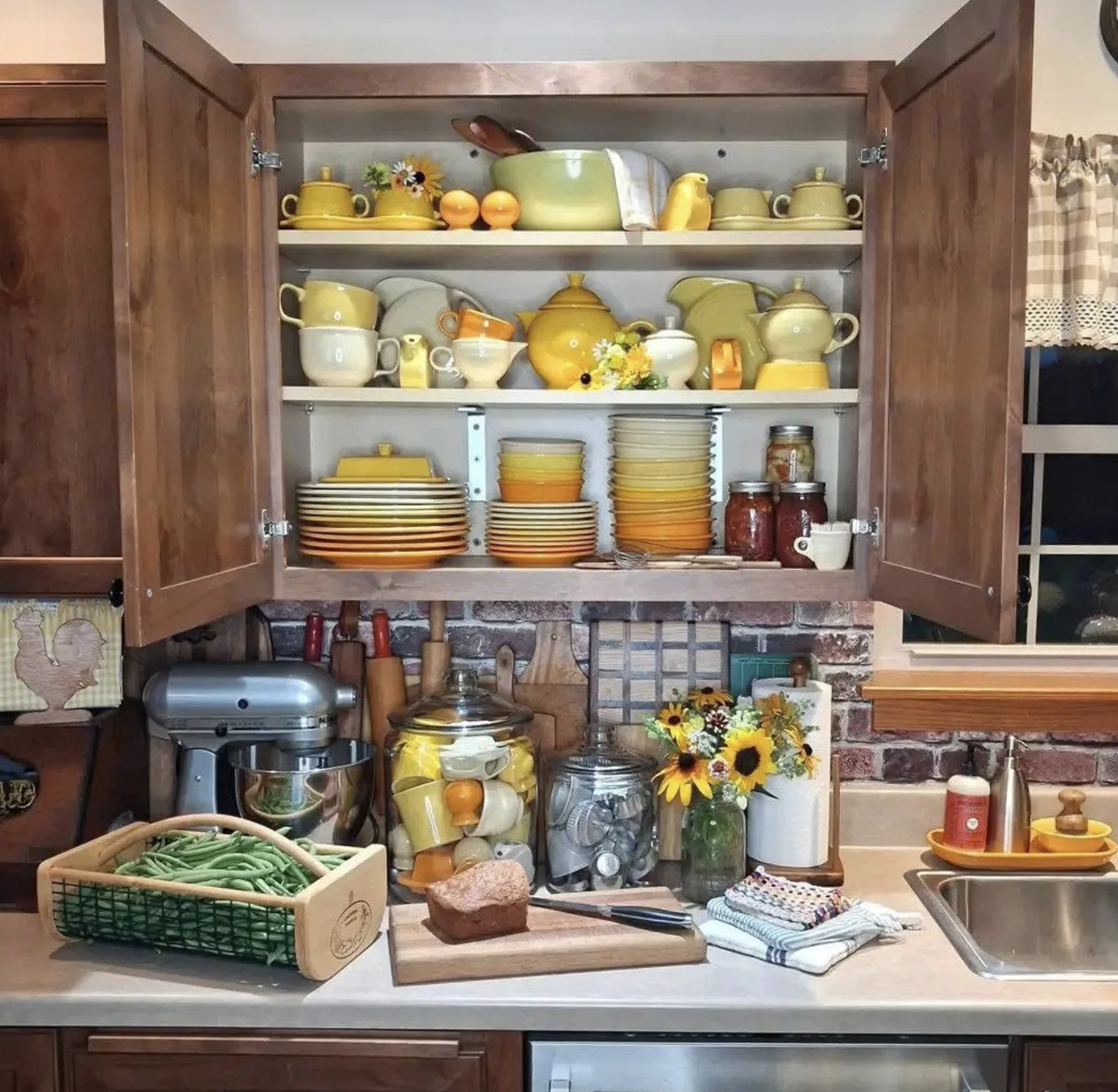 An open cabinet displaying coordinated yellow and cream kitchenware