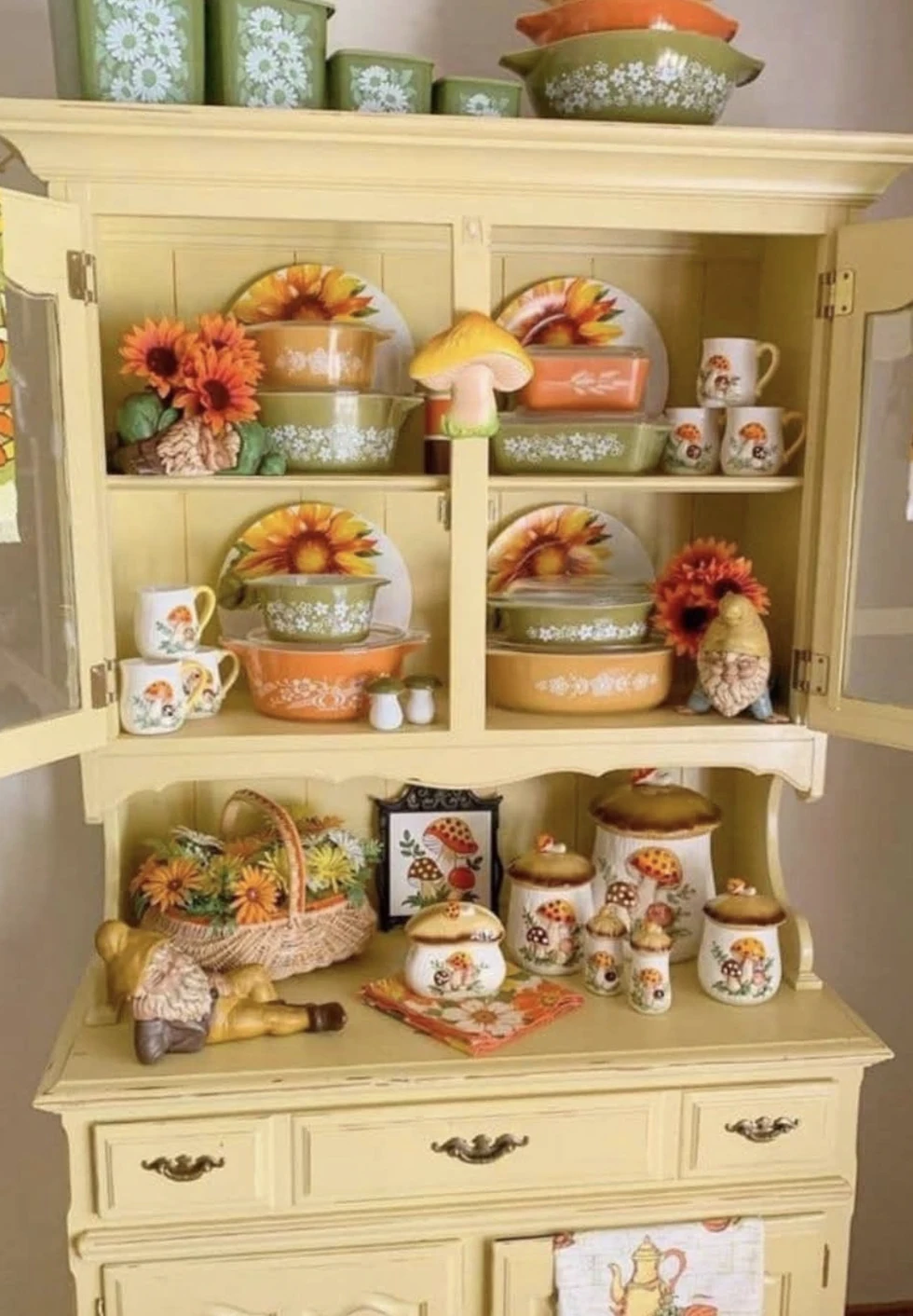 Vintage green and orange kitchenware displayed in a sunny yellow cabinet