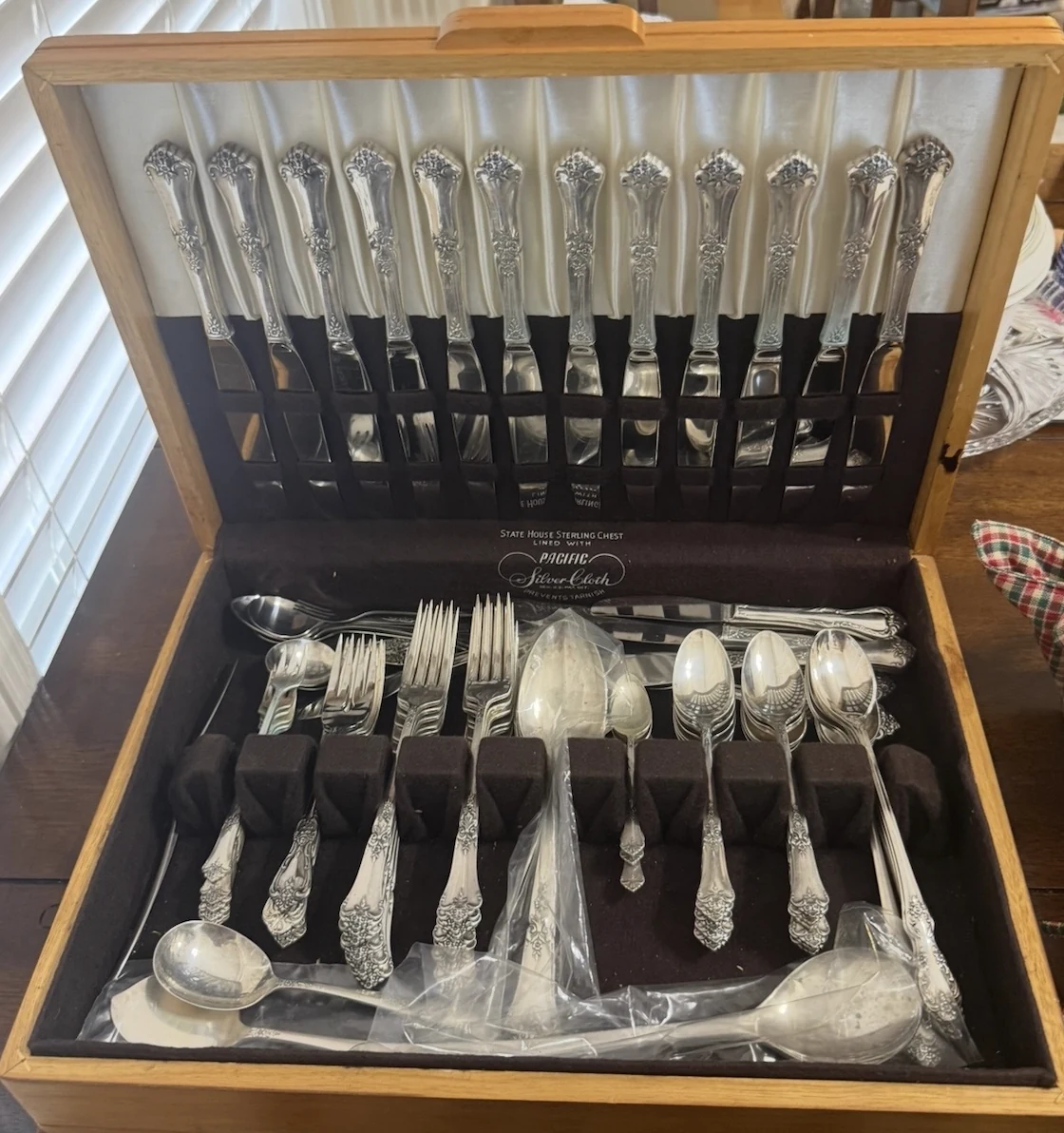 Vintage silver flatware displayed in a wooden chest at a J and M estate sale