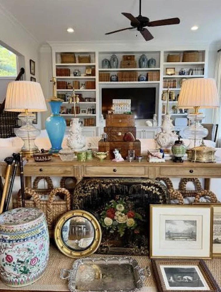 A living room arranged with lamps, framed art, baskets, and collectibles for an upcoming J and M estate sale